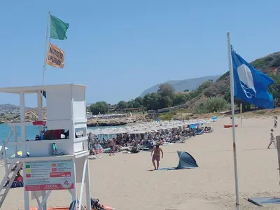 a group of people on a beach with a blue flag at Stylish summer flat, close to beach in Daratso