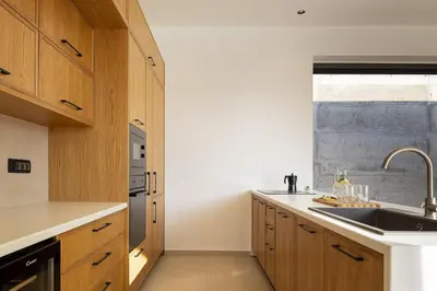 a kitchen with wooden cabinets and a sink at Salisol Villa - Green Oasis in Chania Town