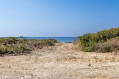a dirt road leading to the ocean on a beach at A to Z in Palaiochóra