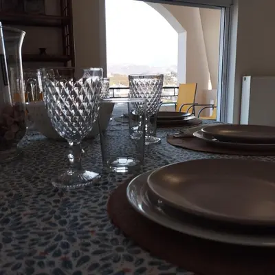 a table with plates and wine glasses on a table at Hillside Escape by the Sea in Daratso