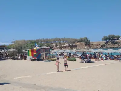 two women standing on a beach with a crowd of people at Hillside Escape by the Sea in Daratso