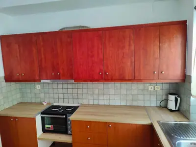 a kitchen with wooden cabinets and a stove top oven at Nikolaos central cozy apartment & free parking in Chania Town