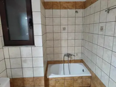 a bath tub in a tiled bathroom with a window at Nikolaos central cozy apartment & free parking in Chania Town