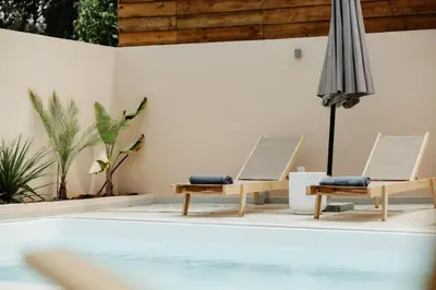 two chairs and an umbrella next to a swimming pool at Roots Villa in Skinés