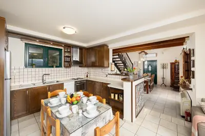a kitchen with wooden cabinets and a table with chairs at Aloni Villa in Káïna
