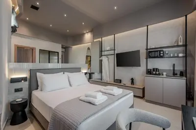 a bedroom with a large white bed and a chair at Amara Luxury Suites With Private Hot Tub in Chania Town