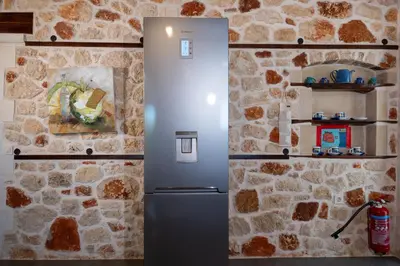 a refrigerator in a kitchen with a stone wall at Villa Resi in Vamos