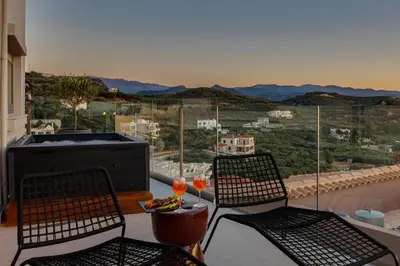 a balcony with two chairs and a table with wine glasses at Alectrona Living Crete, Villa Mezcal in Plataniás