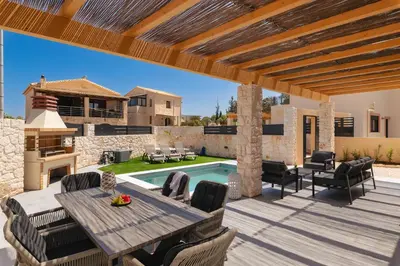a patio with a table and chairs and a pool at LUV Group of 4 Villas in Kathiana in Kathiana