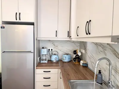 a kitchen with white cabinets and a stainless steel refrigerator at Amfitriti 30meter to beach, 6min Old Town, 2BD 4PL in Chania Town