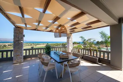 a dining room with a table and chairs on a balcony at Villa Lady Dafni with private heated pool in Maleme
