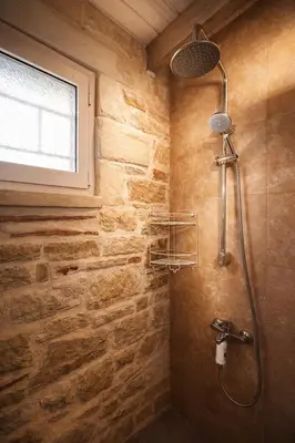 a shower in a bathroom with a stone wall at Mersini Village in Milonianá