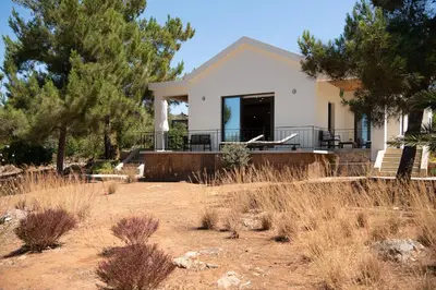 a white house with trees and a yard at Myrtia Beach House in Tersanas