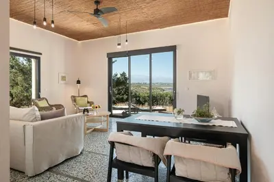 a living room with a dining room table with chairs at Myrtia Beach House in Tersanas