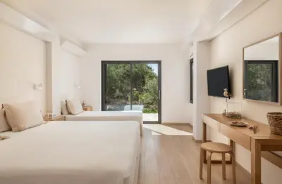 a bedroom with two beds and a desk and a television at Myrtia Beach House in Tersanas