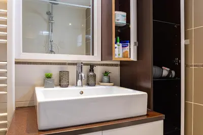 a bathroom with a white sink and a cabinet at Harbour - Spacious Unique 2-Balcony Apartment in Chania Old Town in Chania Town