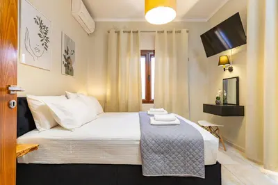 a bedroom with a bed with white sheets and a television at Harbour - Spacious Unique 2-Balcony Apartment in Chania Old Town in Chania Town