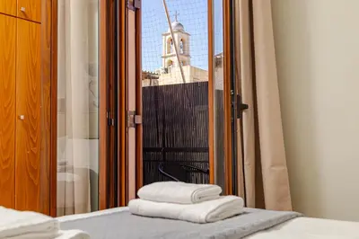 a stack of towels on a bed in front of a window at Harbour - Spacious Unique 2-Balcony Apartment in Chania Old Town in Chania Town