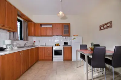a kitchen with wooden cabinets and a table with chairs at Villa Alimedon in Almirida