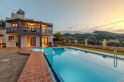 a villa with a swimming pool in front of a house at Anna by Vintage Travel in Troúlous