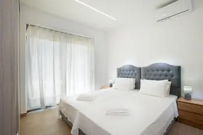 a bedroom with a large white bed with a large window at Villa Sea Breeze in Xamoudhokhórion