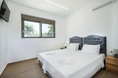 a white bedroom with a large bed and a window at Villa Sea Breeze in Xamoudhokhórion