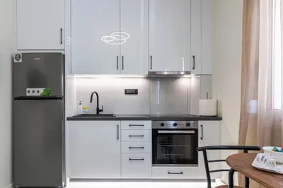 a kitchen with white cabinets and a stainless steel refrigerator at Peonia Apartment Modern Two-Level Stay Near Old Town in Chania Town