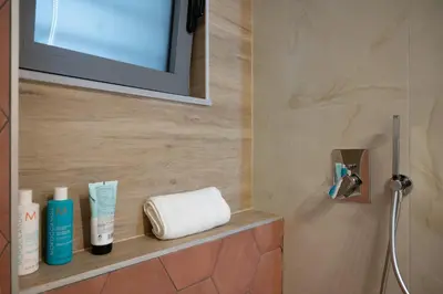 a bathroom with a shelf with towels and a mirror at Lumera Urban Stay - New 2BR Home with Private Parking near Old Town in Chania Town
