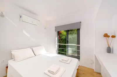 a white bedroom with a bed and a window at Central cozy garden flat in Chania Town