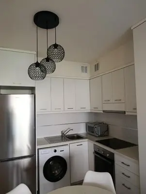 a kitchen with white cabinets and a dishwasher and two lights at Apartment Odysea in Plataniás