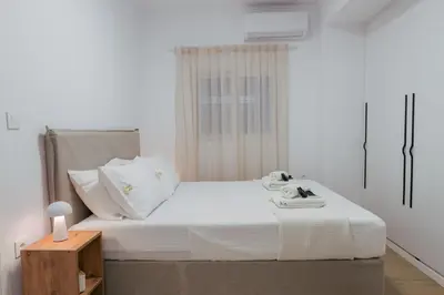 a bedroom with a bed with white sheets and a table at Hanim 2BR Loft Apartment - Garden & Indoor Parking in Chania Town