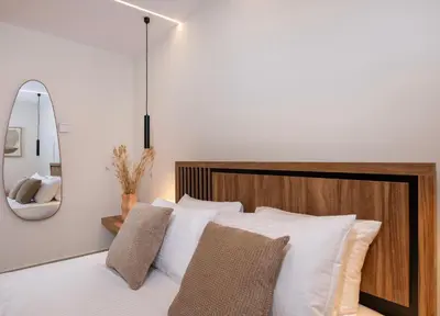 a bedroom with a bed with white pillows and a mirror at Bōw Ground Floor Luxury Apt-In Chania Old Town! in Chania Town