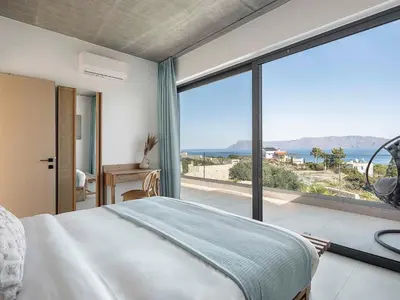 a bedroom with a bed and a large window at Himmel Villas - Seaview luxury & private pools in Kalivianí