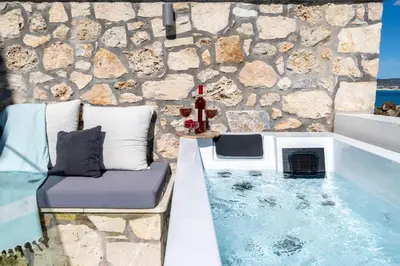 a bath tub with a bench next to a stone wall at Omorphi Seaside Villa in Kalyves