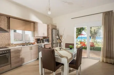 a kitchen with a table with chairs and a dining room at Lila Villas in Stalos