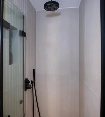 a bathroom with a shower and a light on the wall at Bow Complex Apartment- In the Heart of Old Harbour in Chania Town