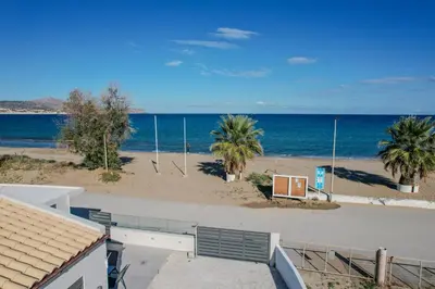 a view of a beach with palm trees and the ocean at Seawhisper Villa in Kalyves