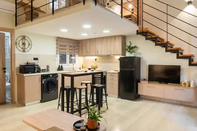 a kitchen with a staircase and a kitchen island with bar stools at La Petite Fleur City apartment Chania in Chania Town