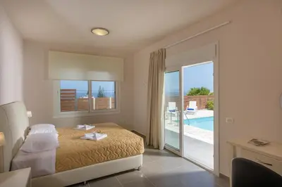 a bedroom with a bed and a view of a pool at Koukos Villas in Stalos