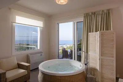 a bathroom with a tub in a room with a window at Koukos Villas in Stalos