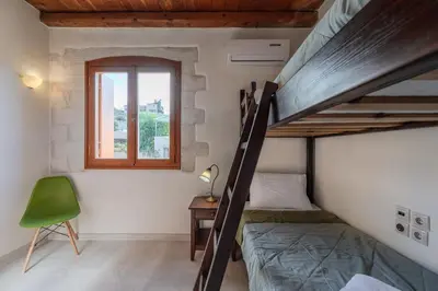 a bedroom with two bunk beds and a green chair at Vamos villa in Vamos