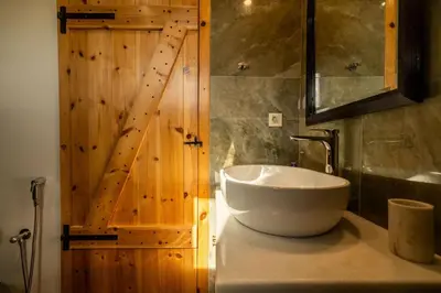 a bathroom with a sink and a wooden door at Villa Falcos by PosarelliVillas in Gavalochori