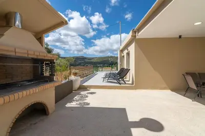a patio with chairs and a fireplace on a house at Huzuri Retreat in Kissamos