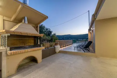 a patio with a brick fireplace on a house at Huzuri Retreat in Kissamos