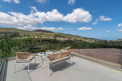 a patio with a table and chairs on a roof at Huzuri Retreat in Kissamos