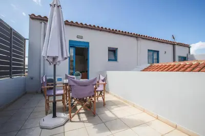 a patio with an umbrella and chairs and a table at Kafkales Penthouse Chania Old Town in Chania Town