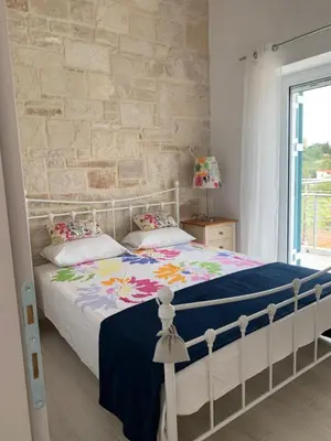 a bedroom with a white bed and a brick wall at villa Elaionas in Tsivarás