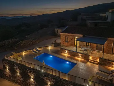 a swimming pool in front of a house at night at To Petrino Stone Mountain Retreat with Private Pool in Rodhopós