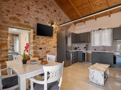 a kitchen with a table and chairs in a room at To Petrino Stone Mountain Retreat with Private Pool in Rodhopós