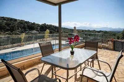 a table with a vase of flowers on a balcony at To Petrino Stone Mountain Retreat with Private Pool in Rodhopós